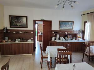 a dining room with tables and chairs and a kitchen at Vontzos Hotel in Achladies