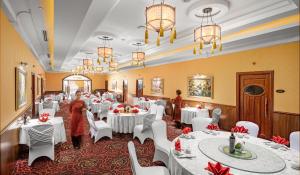 a dining room with white tables and white chairs at Fortuna Hotel Hanoi in Hanoi