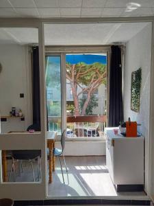 Habitación con ventana grande, mesa y escritorio. en studio parking privé climatisation plage proche, en La Grande-Motte