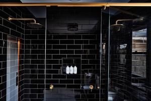 a black tiled shower with three bottles on a shelf at Ruby by Whiskey June in Maryborough