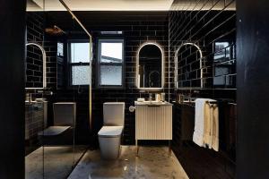 a black bathroom with a toilet and two sinks at Ruby by Whiskey June in Maryborough