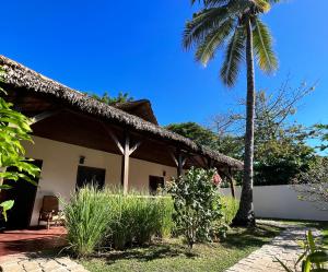 a house with a palm tree in front of it at NatShi Lodge in Ambaro