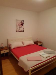 a bedroom with a bed with a red blanket at Apartments Lola in Biograd na Moru