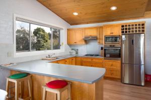 una cucina con armadi in legno e bancone con sgabelli di Seaside Retreat in Rhyll a Rhyll Altre 6 foto