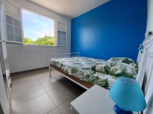 ein blaues Zimmer mit einem Bett und einem Fenster in der Unterkunft KORN LAMBIS in Sainte-Luce