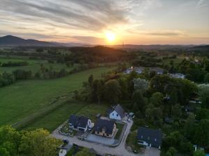 una vista aérea de una casa en un campo con la puesta de sol en Apartamenty Czarna Perła, en Kowary