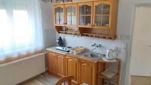a kitchen with wooden cabinets and a sink at Lea apartman in Harkány