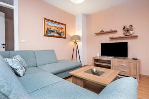 a living room with a blue couch and a tv at Apartment Deluxe in Rovinj