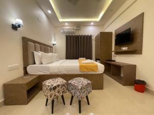 a bedroom with a bed with two chairs and a tv at Yellow Sky in Baga