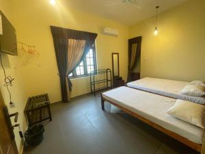 1 dormitorio con 2 camas y ventana en Catray Inn, en Kalmunai