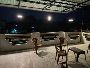2 sillas y una mesa en el balcón por la noche en Catray Inn, en Kalmunai