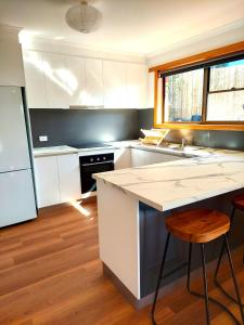 uma cozinha com armários brancos e piso em madeira em Percy's Cottage em Devonport