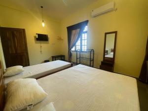 two beds in a room with a mirror and a window at Catray Inn in Kalmunai