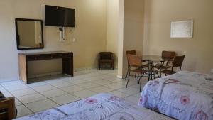 1 dormitorio con cama, mesa y TV en Hotel Hacienda las Higueras, en Tepic