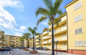 un edificio de apartamentos con palmeras en un aparcamiento en Beautiful Apartment In Caulonia Marina With Kitchenette, en Caulonia Marina