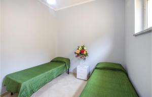 um quarto com duas camas verdes e um vaso de flores em Beautiful Apartment In Caulonia Marina With Kitchenette em Caulonia Marina