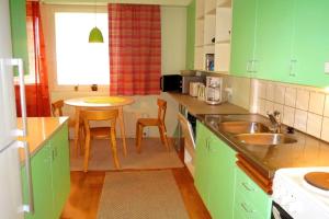 a kitchen with green cabinets and a table with chairs at Retrohenkinen kaksio Nurmeksen keskustassa. in Nurmes