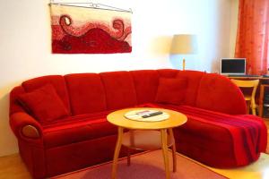 een rode bank in een woonkamer met een tafel bij Retrohenkinen kaksio Nurmeksen keskustassa. in Nurmes