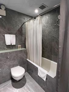 香港的住宿－Hennessy Hotel，浴室配有卫生间、淋浴和浴缸。