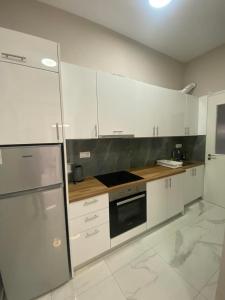 uma cozinha com armários brancos e um forno com placa de fogão em Casa Costera 2 lux apt em Kiato