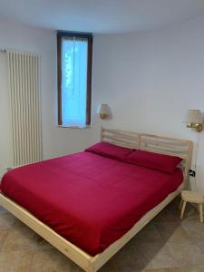 a bedroom with a large bed with a red bedspread at Appartamento La Torre in Predazzo
