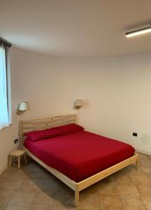 a bedroom with a wooden bed with a red blanket at Appartamento La Torre in Predazzo