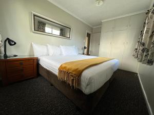 a bedroom with a large bed and a dresser with a mirror at Lake Ruataniwha Holiday Park in Twizel