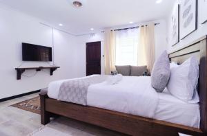 a bedroom with a large white bed and a television at Arabel's Place Riverside Villas in Nanyuki