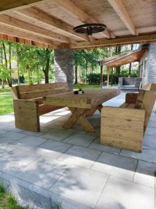 a wooden picnic table and bench under a wooden roof at Exklusives Landhaus Haar, Emsland in Emsbüren