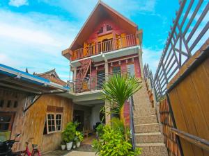 ein rotes Haus mit einem Balkon und einer Palme in der Unterkunft OYO 92558 Bale Datu Homestay in Montongbuwoh