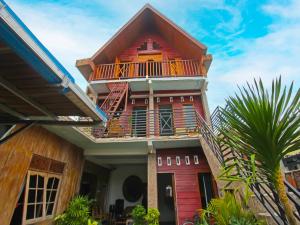 a red house with a balcony and a palm tree at OYO 92558 Bale Datu Homestay in Montongbuwoh