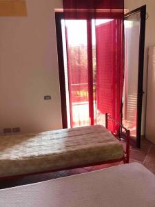 Schlafzimmer mit einem Bett und einem Fenster mit roten Vorhängen in der Unterkunft Villa Serena in Vibonati