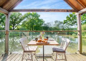 a table on a deck with a view of the water at The Boathouse in Biddenden