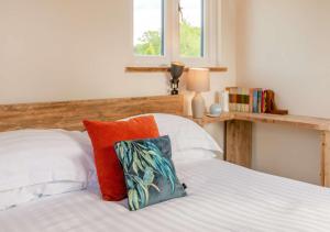 1 dormitorio con 1 cama con almohadas de color naranja y blanco en The Boathouse, en Biddenden