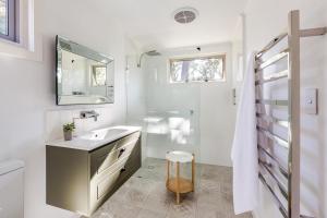 a white bathroom with a sink and a mirror at Hideaway Studio in Dunsborough