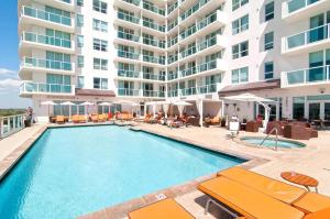 a swimming pool in front of a large apartment building at Stunning 12th Floor Studio In The Heart Of Grove in Miami