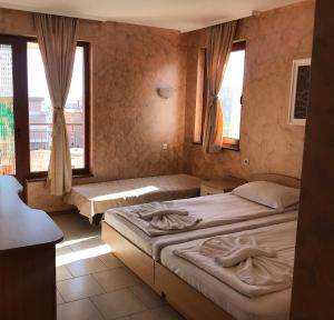 a bedroom with two beds and two windows at Guest House Val and Kate in Sveti Vlas
