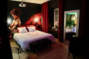 a bedroom with a bed with a painting on the wall at love room gold - les delices rooms in Angers
