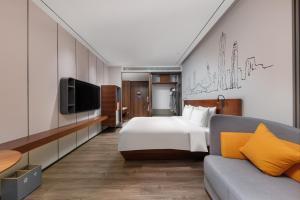 um quarto com uma cama, uma televisão e um sofá em UrCove By Hyatt ShenZhen Bay em Shenzhen