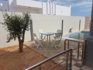 eine Terrasse mit einem Tisch und Stühlen neben einem Pool in der Unterkunft Djerba La Douce in Houmt Souk