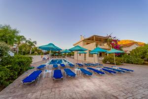 a swimming pool with blue lounge chairs and umbrellas at Amaryllis front beach hotel in Lartos