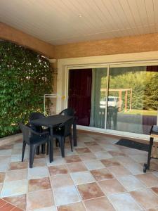 een patio met een zwarte tafel en stoelen op een veranda bij bienvenue chez nous in Badens
