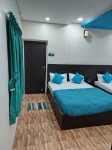 a bedroom with two beds with blue pillows at Hotel Sai Dakshina Inn in Shirdi