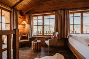 a bedroom with a bed and chairs and windows at Almdorf Sankt Johann in Sankt Johann im Pongau