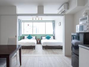 ein Wohnzimmer mit 2 Betten und einem Tisch in der Unterkunft Reality Hakata 2 in Fukuoka