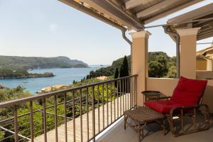 a balcony with a red chair and a view of the ocean at Paleokastritsa Red Gate Flat in Paleokastritsa