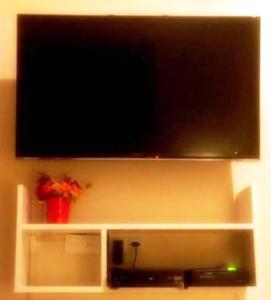 a flat screen tv on top of a white shelf at Estudio Dalia vista para o mar in Rio de Janeiro