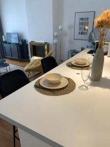 a white table with two plates and a vase on it at Escale citadine au centre d'Avignon, climatisation, appartement de charme, spacieux et lumineux in Avignon