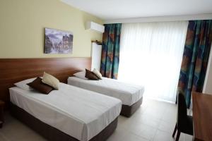 um quarto de hotel com duas camas e uma janela em KALİYE ASPENDOS HOTEL em Antalya