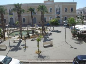 a courtyard with benches and palm trees in front of a building at Gallipoli Al Corso in Gallipoli